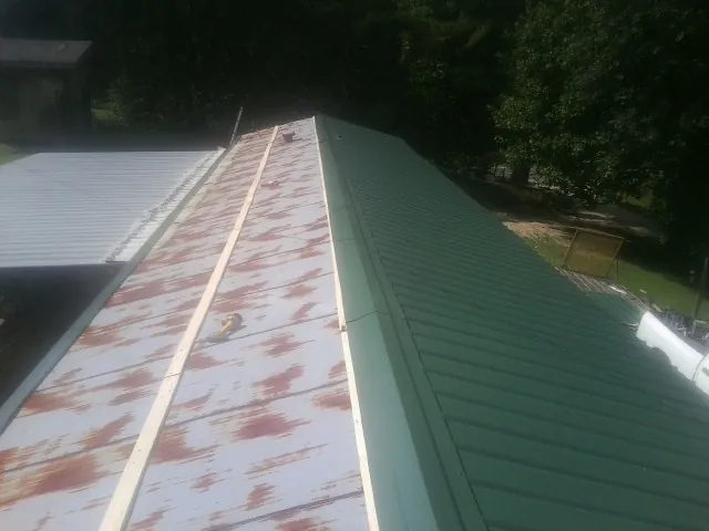 Old rusted panels beside newly installed green metal roofing — Wind Damage Roof Repair by Roofing Brothers in Tybee Island