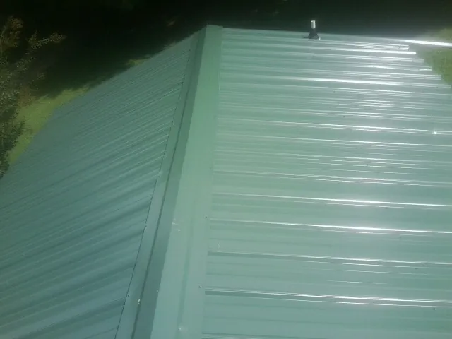 New green metal panels meeting at the ridge of a roof — Flat Roof Repair work by our crew in Tybee Island