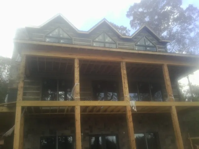 Dormers and porch framing on a large log home under construction — Roof Coating work by our crew in Tybee Island