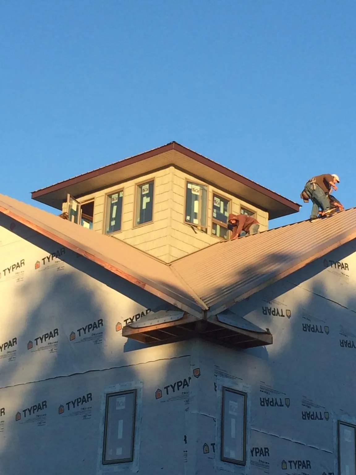Roofers working around a rooftop cupola on a new metal roof at sunset — Roof Waterproofing in Tybee Island by Roofing Brothers